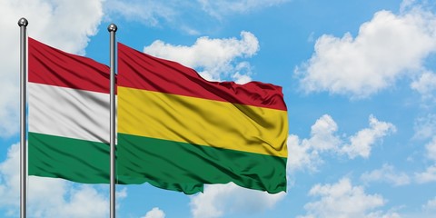 Hungary and Bolivia flag waving in the wind against white cloudy blue sky together. Diplomacy concept, international relations.