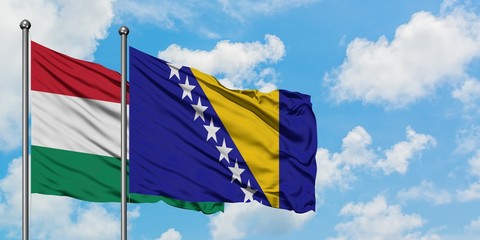 Hungary and Bosnia Herzegovina flag waving in the wind against white cloudy blue sky together. Diplomacy concept, international relations.