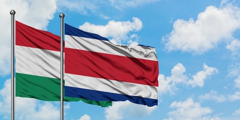 Hungary and Costa Rica flag waving in the wind against white cloudy blue sky together. Diplomacy concept, international relations.