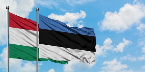 Hungary and Estonia flag waving in the wind against white cloudy blue sky together. Diplomacy concept, international relations.