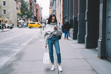 Trendy woman surfing smartphone at street