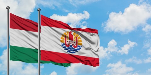 Hungary and French Polynesia flag waving in the wind against white cloudy blue sky together. Diplomacy concept, international relations.