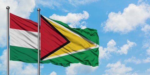 Hungary and Guyana flag waving in the wind against white cloudy blue sky together. Diplomacy concept, international relations.