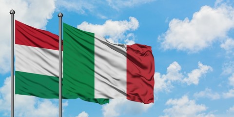 Hungary and Italy flag waving in the wind against white cloudy blue sky together. Diplomacy concept, international relations.