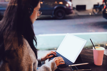 Young woman typing on tablet in cafe with street view