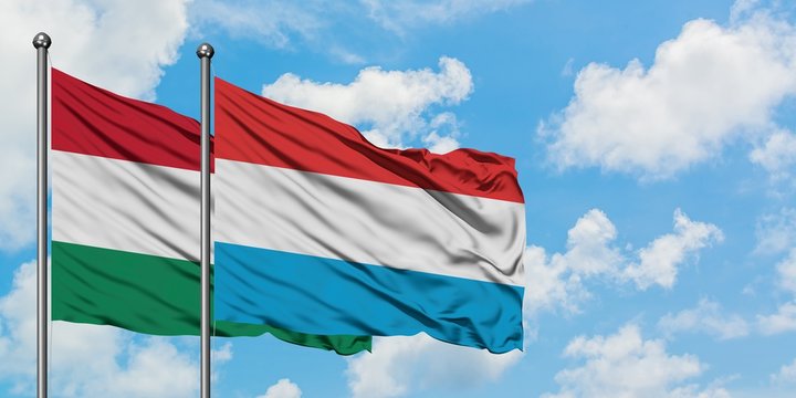 Hungary and Luxembourg flag waving in the wind against white cloudy blue sky together. Diplomacy concept, international relations.