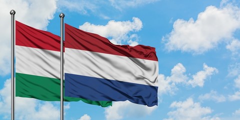Hungary and Netherlands flag waving in the wind against white cloudy blue sky together. Diplomacy concept, international relations.