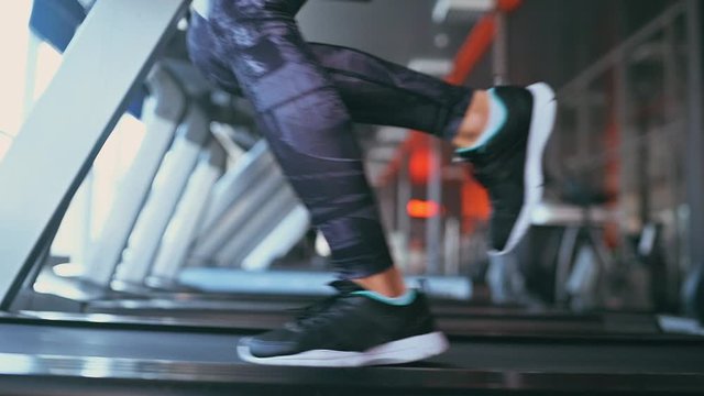 Female feet sneakers woman treadmill running in gym fitness centre, slow motion. Side view