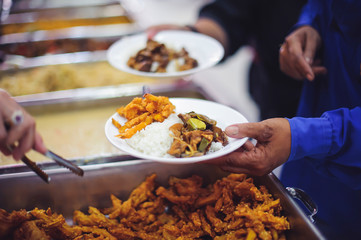 The concept of food needs in society : The recipient's hand holds a dish to request free charity food from a volunteer.