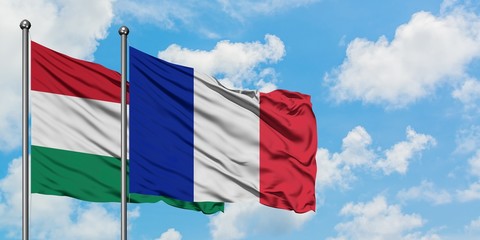 Hungary and Reunion flag waving in the wind against white cloudy blue sky together. Diplomacy concept, international relations.