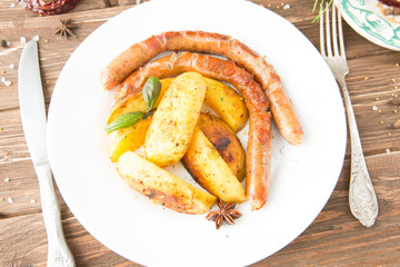 Grilled sausages and mashed potato on a white plate and wooden background