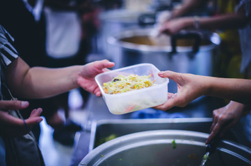 The concept of food needs in society : The recipient's hand holds a dish to request free charity food from a volunteer.