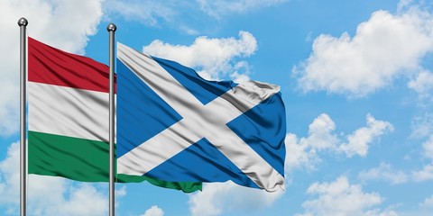 Hungary and Scotland flag waving in the wind against white cloudy blue sky together. Diplomacy concept, international relations.