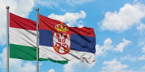 Hungary and Serbia flag waving in the wind against white cloudy blue sky together. Diplomacy concept, international relations.