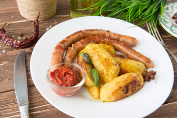 Roasted sausage served with french fries and fresh rosemary. Symbolic image. Concept for a tasty and hearty meal. Close up