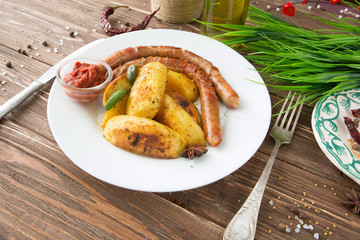 Grilled sausages and mashed potato on a white plate and wooden background