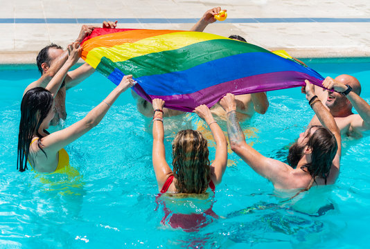 Group of people inside the pool waving a rainbow lgts flag