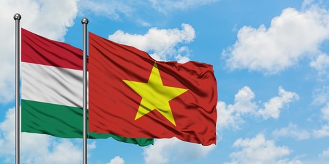 Hungary and Vietnam flag waving in the wind against white cloudy blue sky together. Diplomacy concept, international relations.