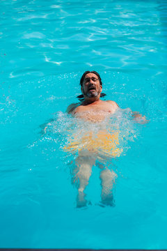 Vertical photo of a man swimming backwards in a pool