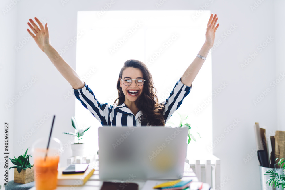 Wall mural young attractive female sitting at table with raised arms