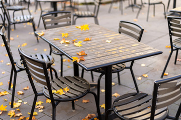 Empty wooden table in the outdoor autumn cafe with metallic black chairs