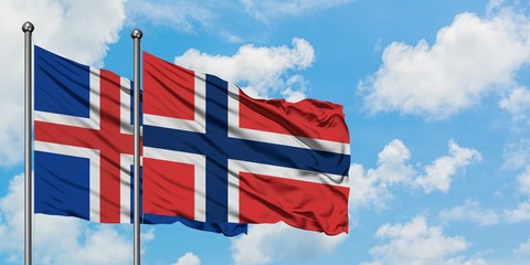 Iceland and Norway flag waving in the wind against white cloudy blue sky together. Diplomacy concept, international relations.