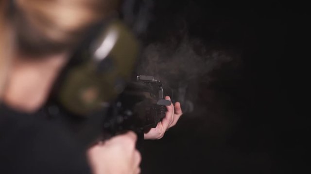 Automatic round bullet firing in slow motion by a woman at a range, closeup