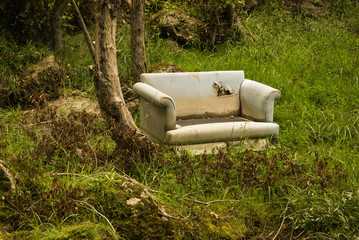 Old sofa in a forest an example of fly tipping or illegal dumping