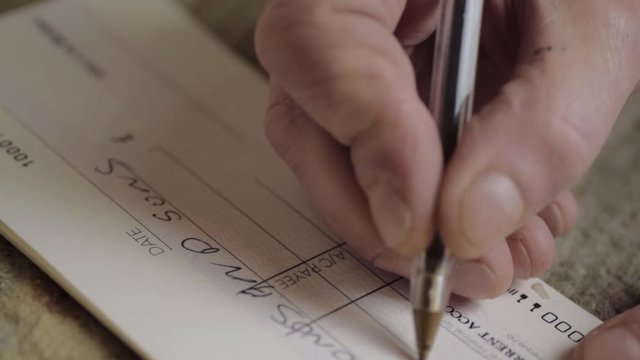 Hand writing a banking check to pay bills