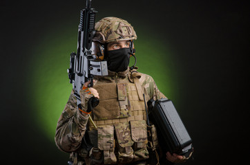 a male soldier in military clothes with a weapon on a dark background