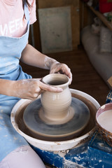 Fototapeta na wymiar Girl Potter sculpts a pitcher of clay on a Potter's wheel.