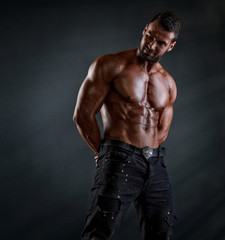 Fototapeta na wymiar Handsome Shirtless Muscular Male Fitness Model Posing in Black Jeans