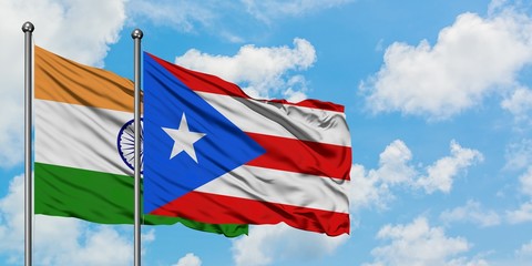 India and Puerto Rico flag waving in the wind against white cloudy blue sky together. Diplomacy concept, international relations.