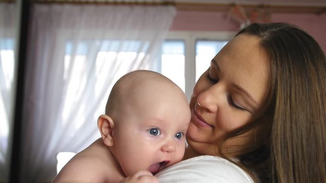 Mother and Baby. Happy young mother hugs chubby baby. Close up shot.