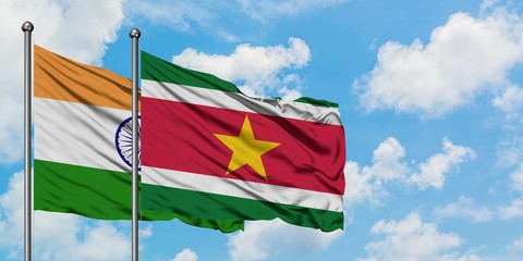 India and Suriname flag waving in the wind against white cloudy blue sky together. Diplomacy concept, international relations.