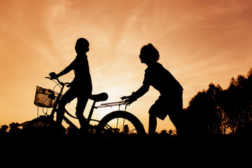 Silhouette of lifestyle children active playing bicycles on summer outside - 300945396