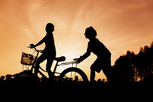 Silhouette of lifestyle children active playing bicycles on summer outside