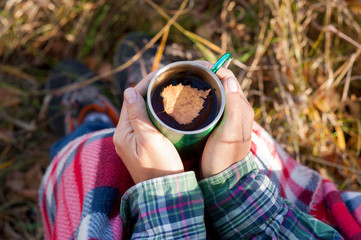 Autumn concept. Cup of tea with fallen yellow leaf in female hands outdoor