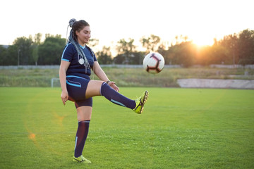 young woman kicks a soccer ball with her foot. Not sporty girl, on the green grass, football field