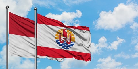 Iraq and French Polynesia flag waving in the wind against white cloudy blue sky together. Diplomacy concept, international relations.