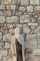 portrait of young European Muslim women with hijab. Stone wall is in her background. She is happy and relaxed.