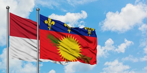 Iraq and Guadeloupe flag waving in the wind against white cloudy blue sky together. Diplomacy concept, international relations.