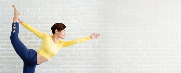 Portrait of a short-hair Asian woman wearing a yellow sportswear Blue pants Doing yoga activities...