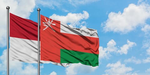 Iraq and Oman flag waving in the wind against white cloudy blue sky together. Diplomacy concept, international relations.