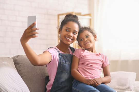 African teen girl taking selfie with her baby sister