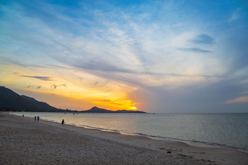 Koh Samui, Thailand - July 30, 2019 - Lamai Beach. People walking on the beach of the Gulf of Thailand at sunrise