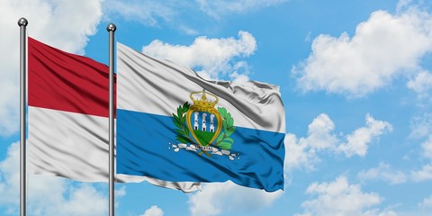 Iraq and San Marino flag waving in the wind against white cloudy blue sky together. Diplomacy concept, international relations.