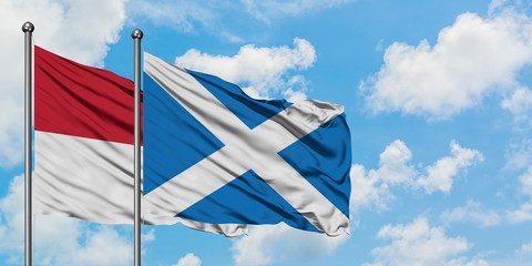 Iraq and Scotland flag waving in the wind against white cloudy blue sky together. Diplomacy...