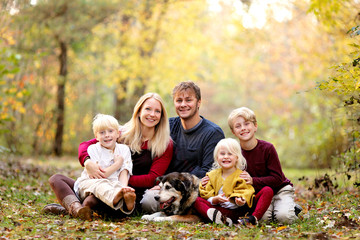 Portrait of Happy Young Family with three Cute, Smiling Children and their Pet Dog on Autumn Day