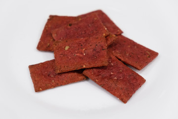 Healthy beetroot crackers in white bowl. cookies from beets on white background. Soft focus. Motion blur.